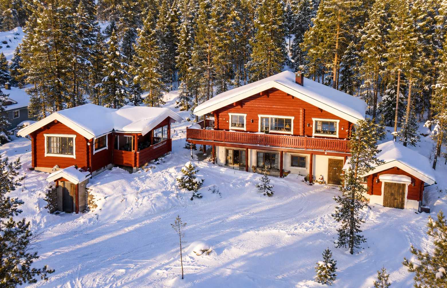 Myrvägen 7 i Tandådalen, vinter: två röda timmerhus i snön bland granar